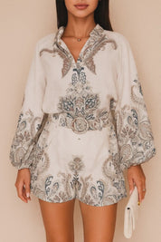 Short lookbook video showing the set in grey paisley and pink floral from front, three-quarter and back views; blouse with billowed sleeves and matching belted shorts.