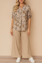 Short lookbook video of an apricot floral blouse and beige wide-leg pants two-piece set; split V-neck, roll-tab sleeves and airy, relaxed fit shown in studio lighting.