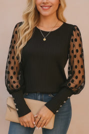 Black rib-knit blouse with sheer polka-dot mesh sleeves, button cuffs and round neckline — studio lookbook video.
