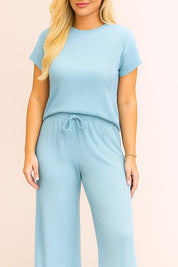 Front detail of the ribbed knit top and waistband, showing the round neckline, fine rib texture and the adjustable drawstring at the waist.