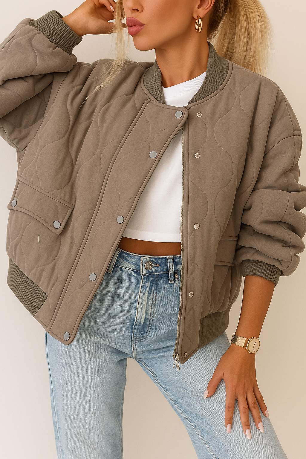 Front detail view of a taupe quilted bomber jacket with rib-knit collar and cuffs, zip front with snap-button placket, and snap-flap patch pockets.