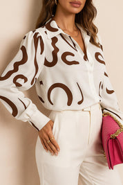 Women’s white-and-brown abstract-print button-up shirt with collared neck and long sleeves, relaxed drape — front three-quarter view.