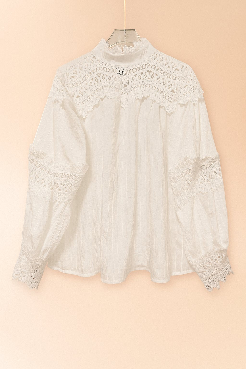 Hanger flatlay, front view of the white high-neck blouse showing the lace yoke and sleeve lace bands with scalloped edge.