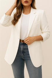 Front view of a white longline blazer with notched lapel, single-breasted front, long sleeves and welt pockets.