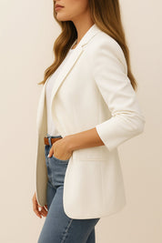 Left side view of the white longline blazer with notched lapel, long sleeves and welt pocket at the hip.