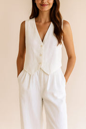 Close front view of the white vest and trousers highlighting the button closure and pleated waist.