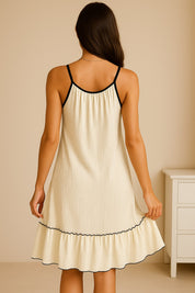 White tiered ruffled lounge dress with adjustable straps, black contrast trim and clean ruffle hem — back view.