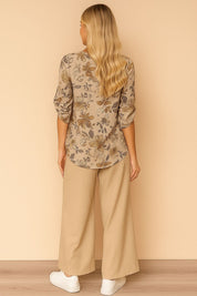 Back view of the apricot floral blouse and beige wide-leg pants set showing the allover print and straight back hem