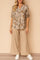 Two‑piece set — apricot floral split V‑neck blouse with roll‑tab sleeves and beige wide‑leg pants, relaxed drape — front view.
