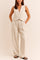 Front view of an apricot sleeveless V-neck vest and pleated wide-leg pants set with button closure and side pockets.