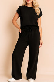 Centered front view of the black ribbed lounge set with drawstring waist trousers and relaxed fit.