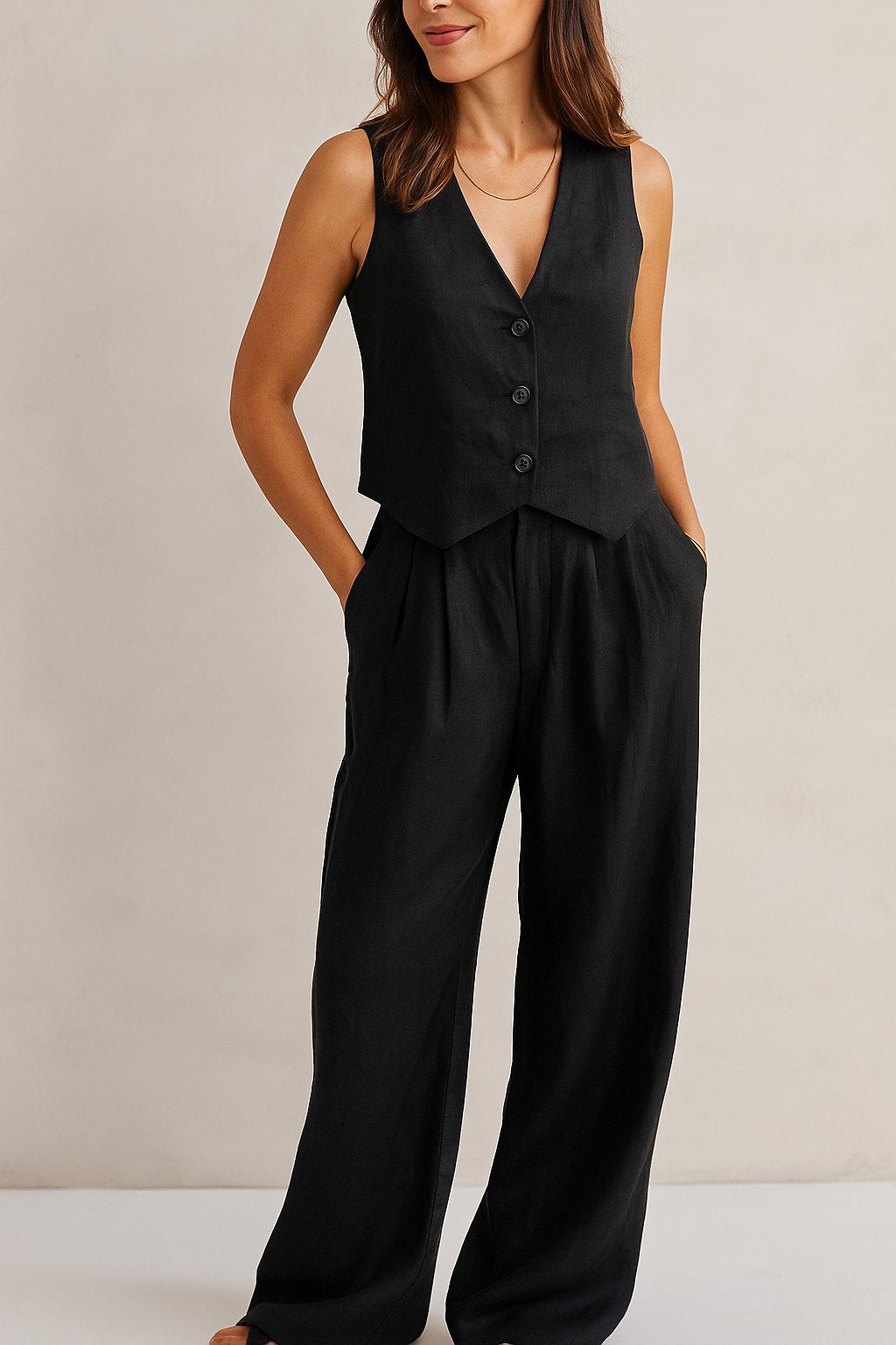 Front three-quarter view of the black vest and wide-leg pants set; V-neck, buttons and side pockets visible.