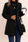 Front three-quarter view of a women’s black tailored button-up coat with notched lapel, gold-tone buttons, long sleeves and a straight hem