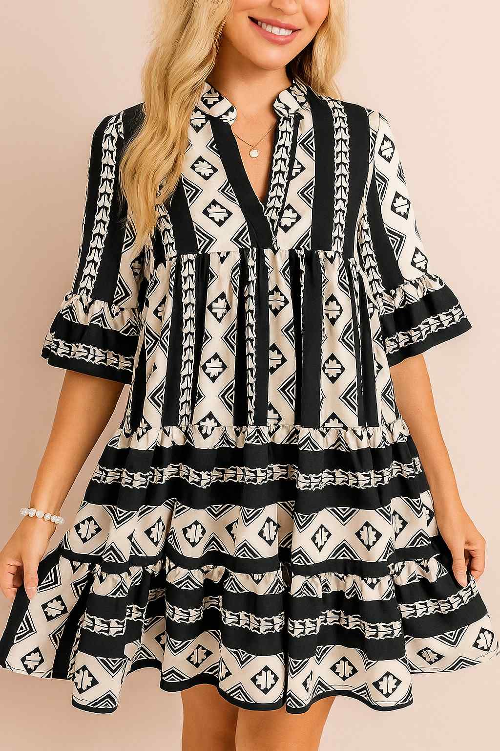 Women’s black-and-white boho geometric tiered mini dress with notched neckline and flared half sleeves — front view.