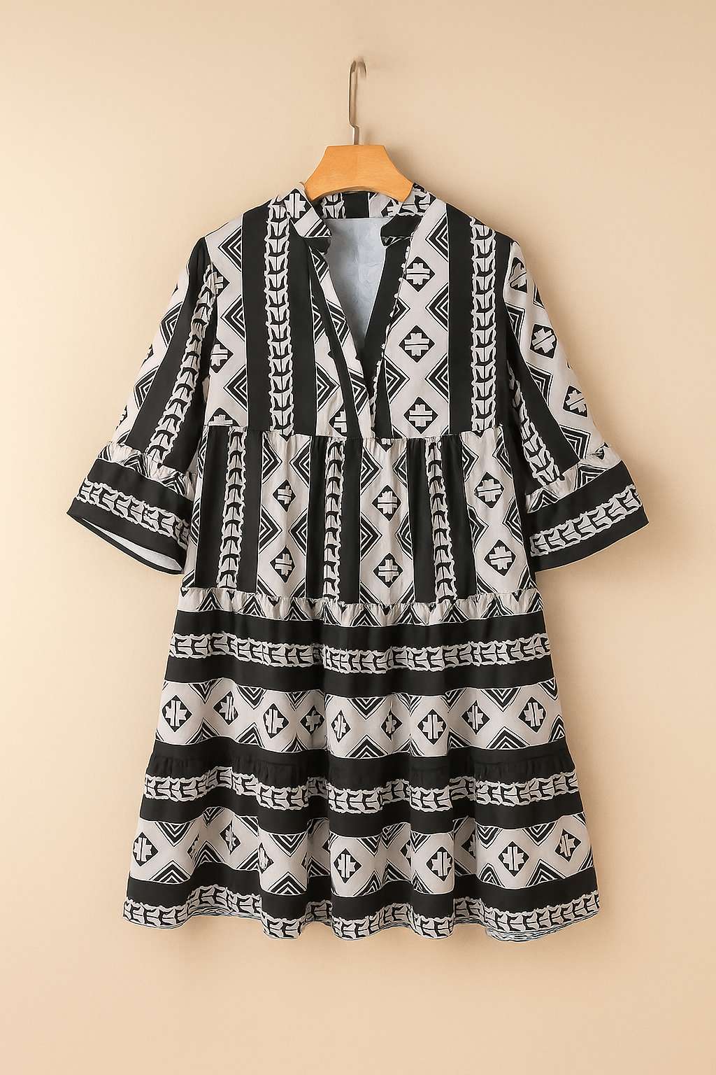 Black-and-white boho geometric tiered mini dress with notched neckline and flared half sleeves — hanger front view