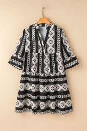 Black-and-white boho geometric tiered mini dress with notched neckline and flared half sleeves — hanger front view