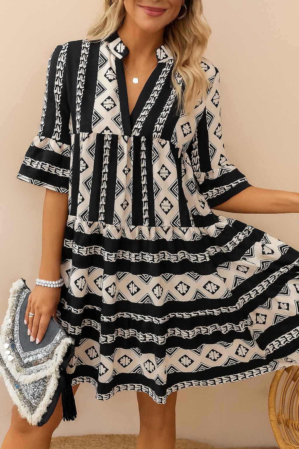 Black-and-white boho geometric tiered mini dress with notched neckline and relaxed A-line drape — front three-quarter view