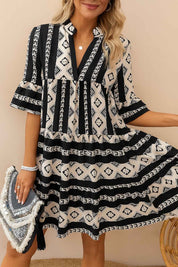 Black-and-white boho geometric tiered mini dress with notched neckline and relaxed A-line drape — front three-quarter view