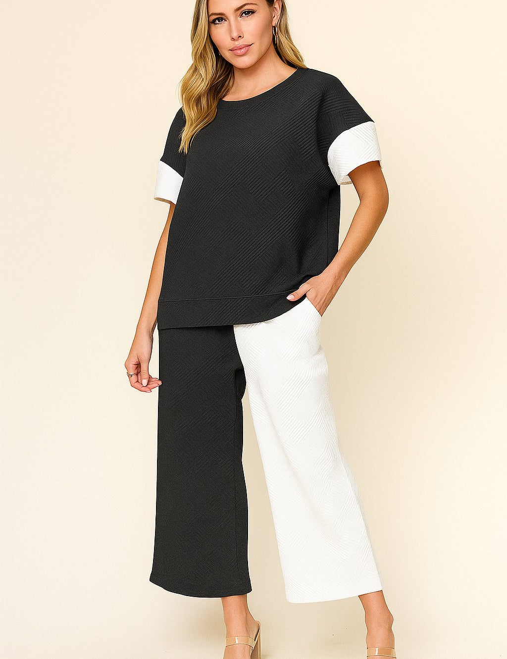 Front view of a women’s black and white colorblock textured short-sleeve top with matching wide-leg pants on an elastic waist