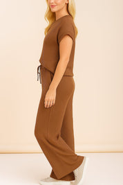 Left side view of the brown ribbed lounge set; short sleeves, exposed front seam and wide-leg silhouette.