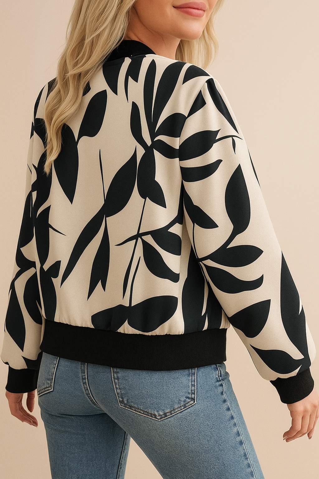 Back three-quarter view of the cream-and-black abstract-print bomber jacket showing the rib-knit hem and allover print.