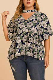 Straight front view of the dark blue floral blouse with cutout choker V-neckline and flutter sleeves; relaxed fit with curved hem