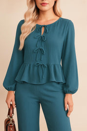 Front detail view of the dusty blue set showing the keyhole tie-neck and peplum seam above the wide-leg pants