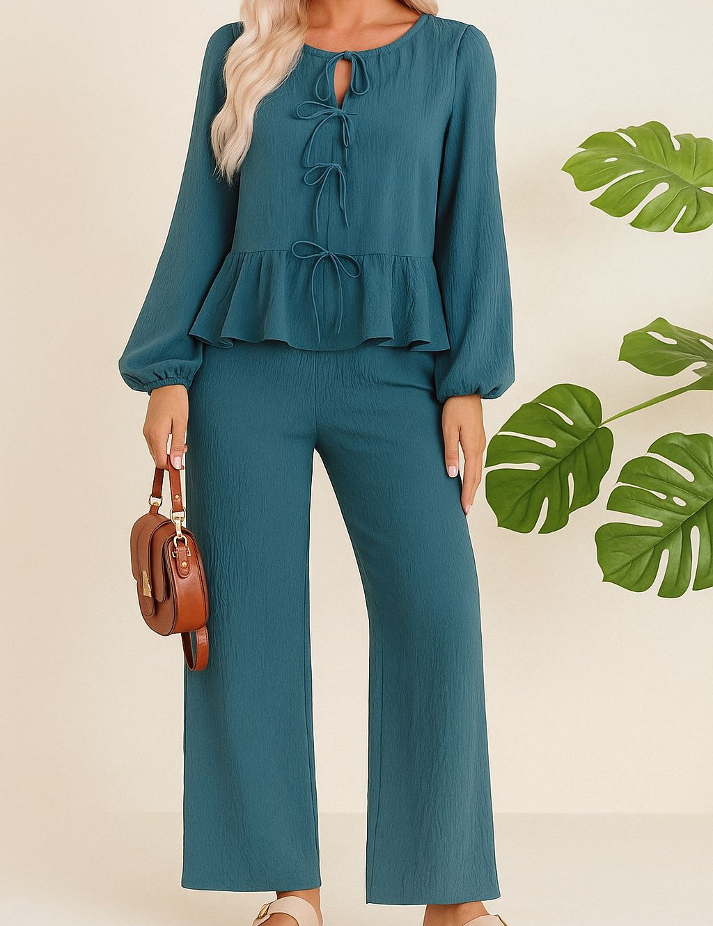 Front view of a dusty blue tie-front peplum blouse paired with wide-leg pants; elastic waist and relaxed fit.