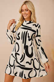 Woman wearing a flowy mini dress with long puff sleeves and bold black abstract print on beige background