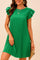 Woman standing in a green pleated mini dress with ruffle sleeves, holding a straw clutch — elegant summer outfit