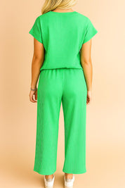 Back three-quarter view of the green ribbed lounge set showing the relaxed silhouette from hip to hem and the vertical rib texture under studio light.