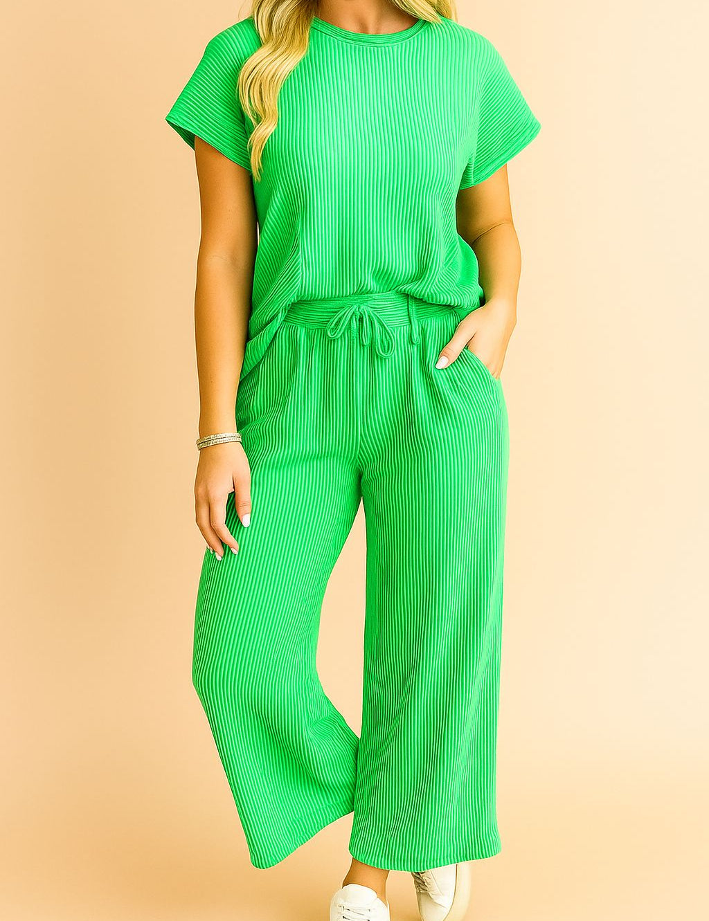 Front detail of the green ribbed knit top highlighting the round neckline and fine rib texture; drawstring waistband and pocket entry partially visible.