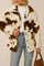 Front view of an ivory and brown cow-print fuzzy button-up jacket with a shirt collar, long sleeves and patch pockets