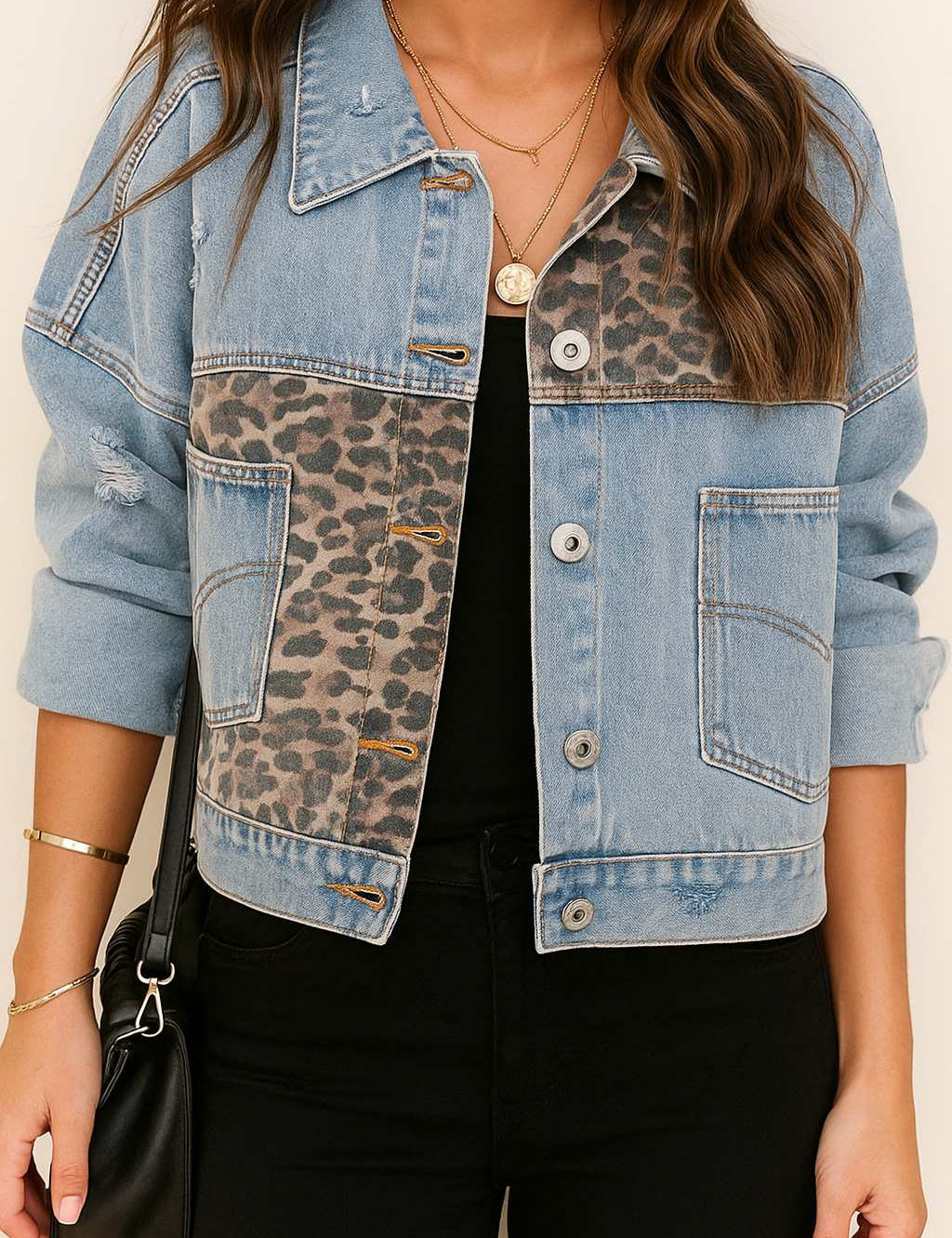 Front view of a women’s light-wash denim jacket with drop-shoulder cut, leopard-panel inserts across the chest and body, light distressing, button front and slant pockets.