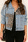 Front view of a women’s light-wash denim jacket with drop-shoulder cut, leopard-panel inserts across the chest and body, light distressing, button front and slant pockets.