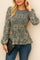 Front three-quarter view of a women’s navy damask jacquard smocked peplum blouse with a round neckline and long sleeves with elastic cuffs.