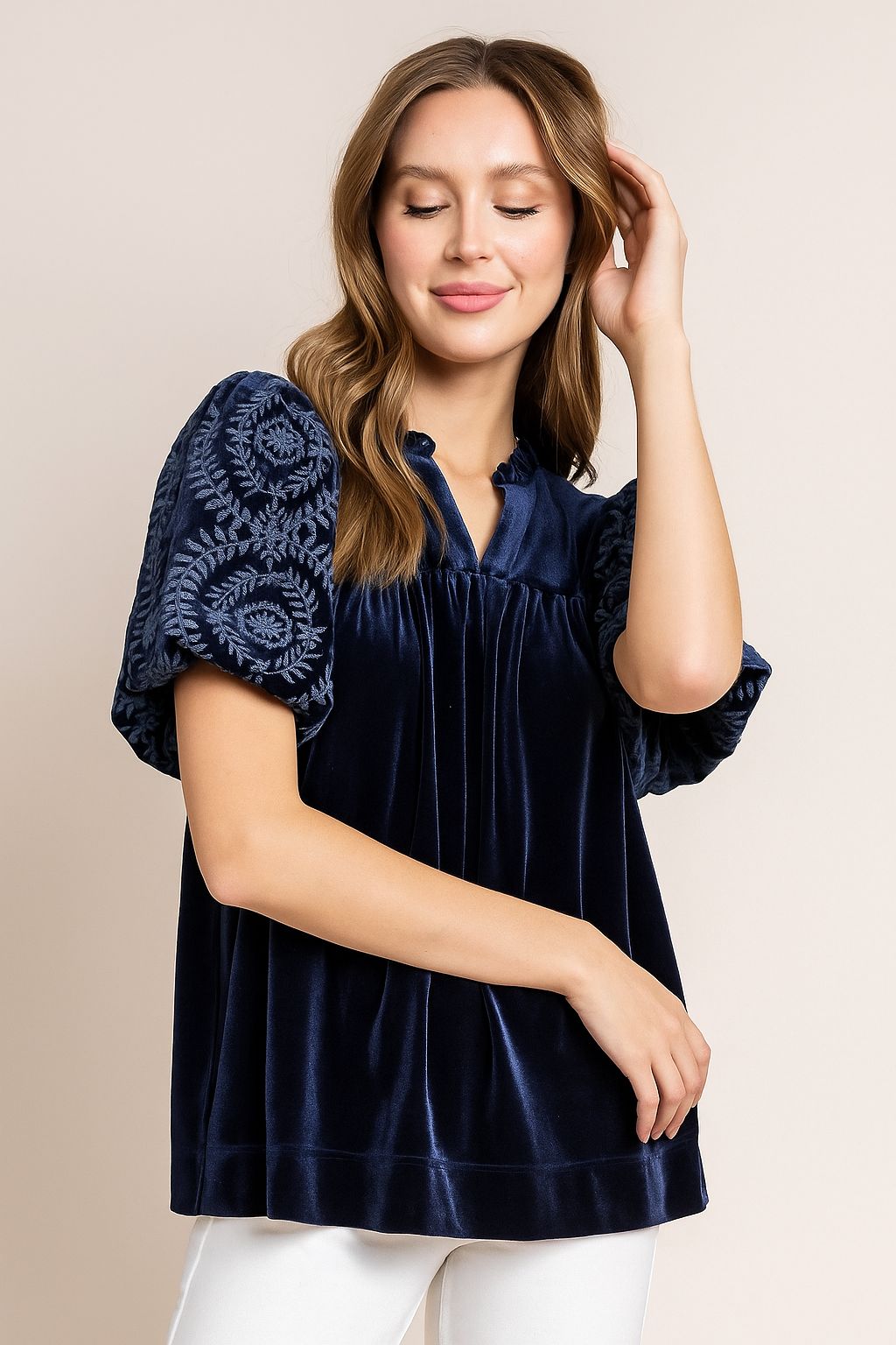 Navy velvet blouse with embroidered puff sleeves and soft notched neckline, easy relaxed silhouette — seated front view.