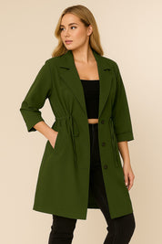 Alternate left three-quarter view of the olive green plus-size lapel trench coat; button placket, drawstring channel and slant pocket visible.