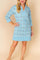 Women’s pastel-blue floral tunic dress with split V-neck and striped trim at collar, cuffs and hem, three-quarter sleeves — front three-quarter view.
