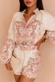 Close front view of the pink floral set with billowed sleeves and a covered-button placket; shorts belt and pleats visible.