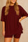 Plus size woman wearing an oversized burgundy lounge set with round neck top and matching shorts