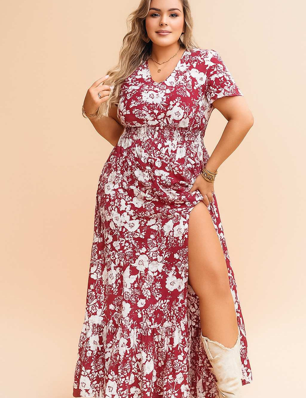 Confident woman in a red floral V-neck maxi dress with side slit, styled with white boots — perfect boho-chic summer outfit.