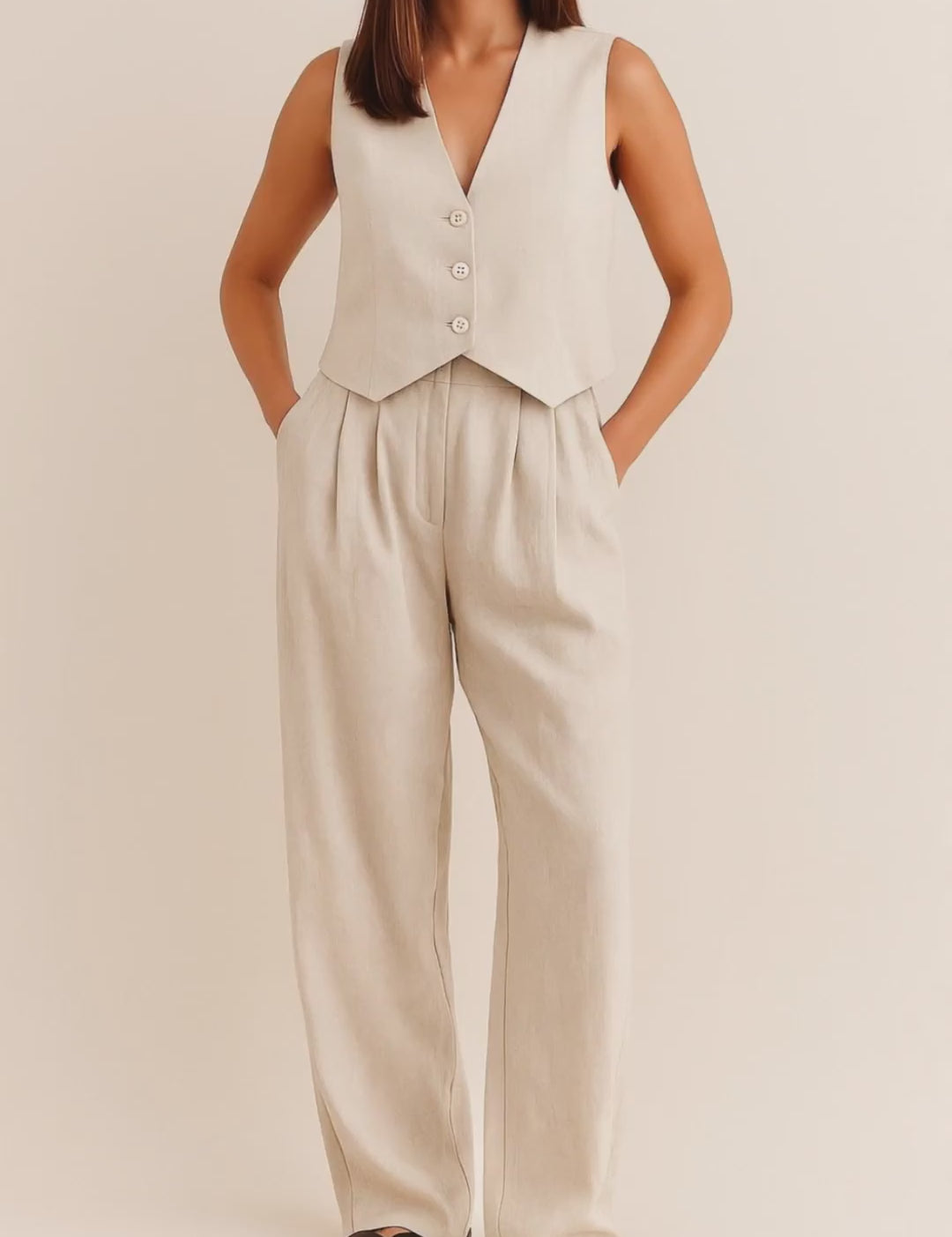 Front view of an apricot sleeveless V-neck vest and pleated wide-leg pants set with button closure and side pockets.