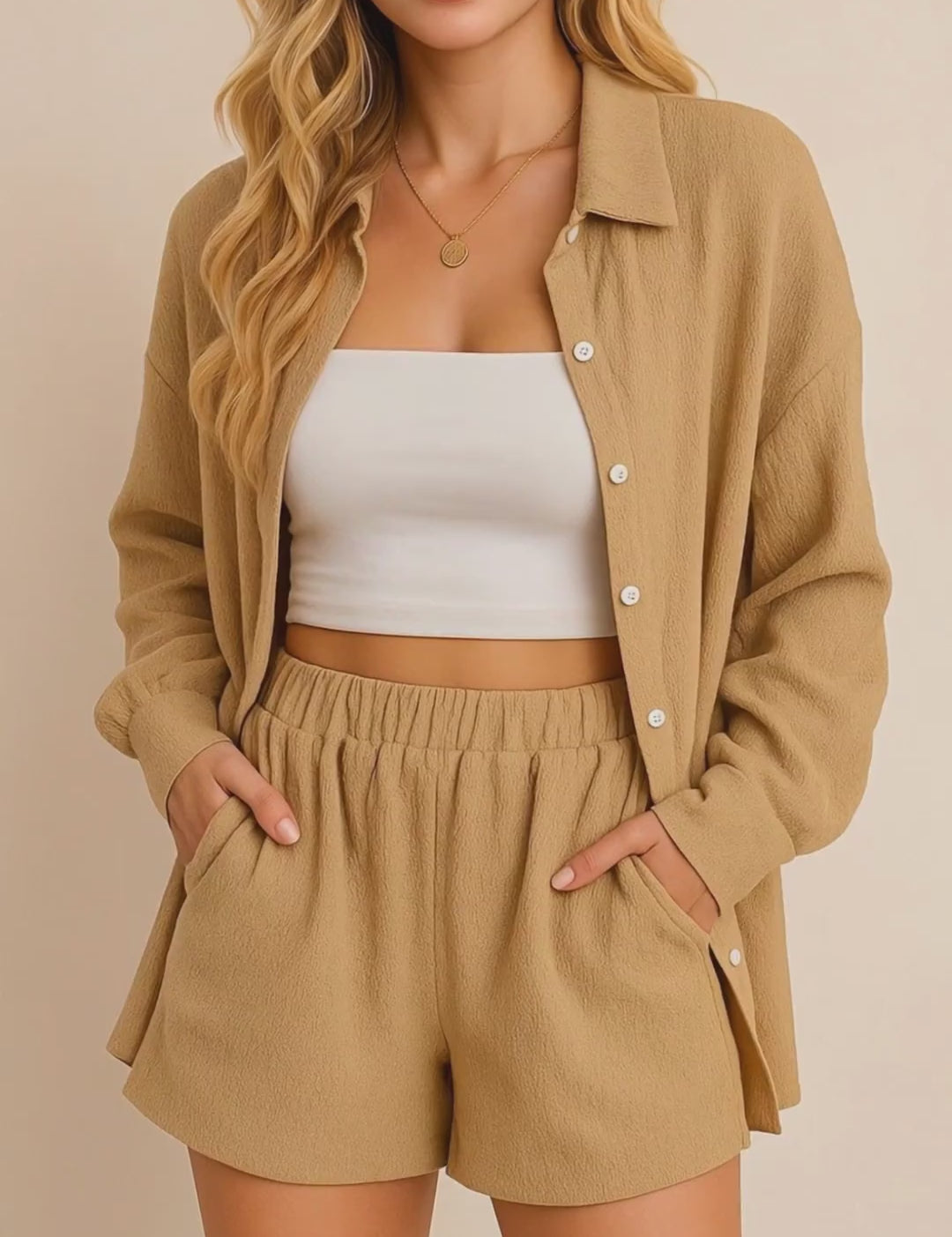 Short lookbook video of a tan crinkle button-up shirt & shorts set showing long sleeves, elastic-waist shorts and side-seam pockets, presented in studio lighting.