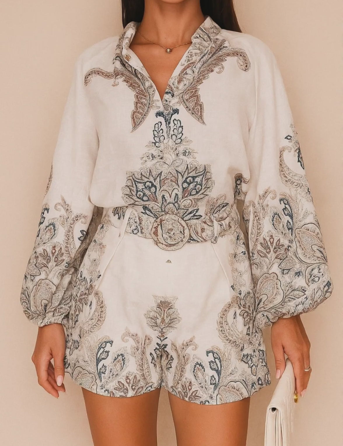 Short lookbook video showing the set in grey paisley and pink floral from front, three-quarter and back views; blouse with billowed sleeves and matching belted shorts.