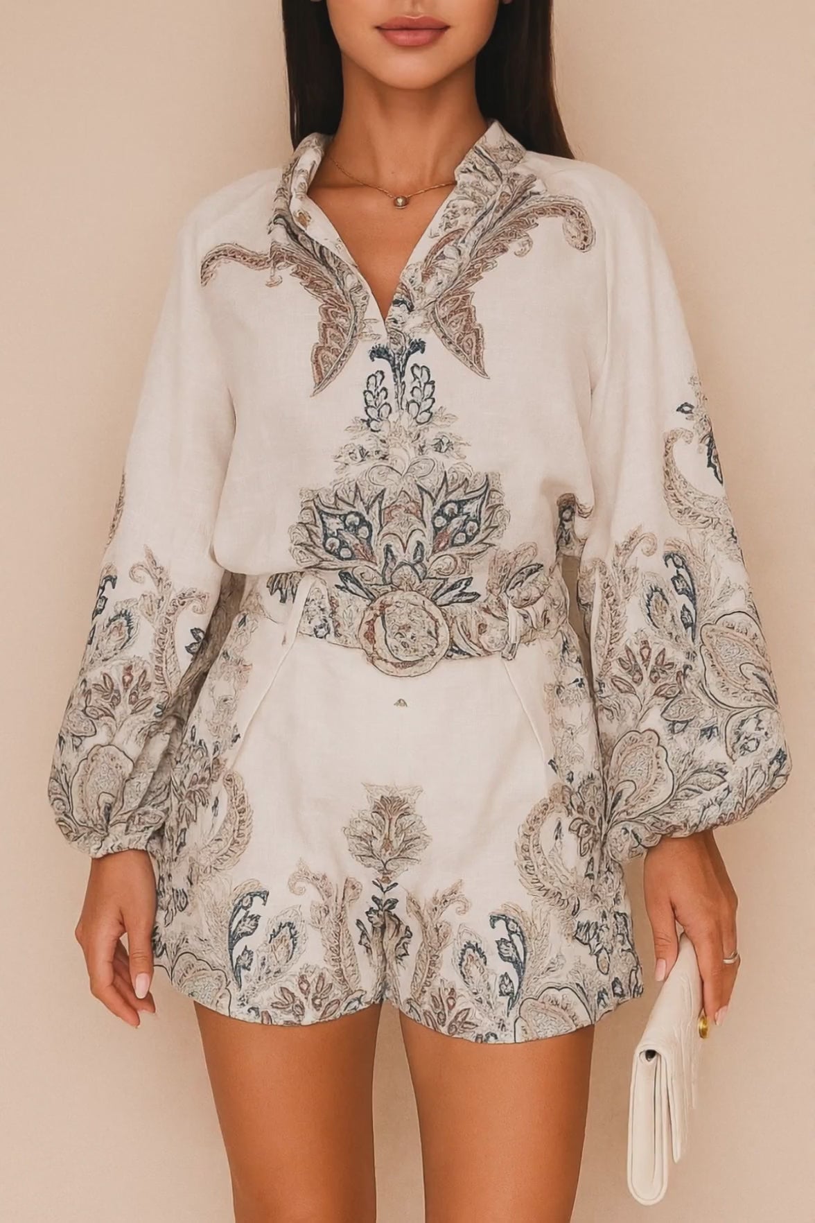 Short lookbook video showing the set in grey paisley and pink floral from front, three-quarter and back views; blouse with billowed sleeves and matching belted shorts.