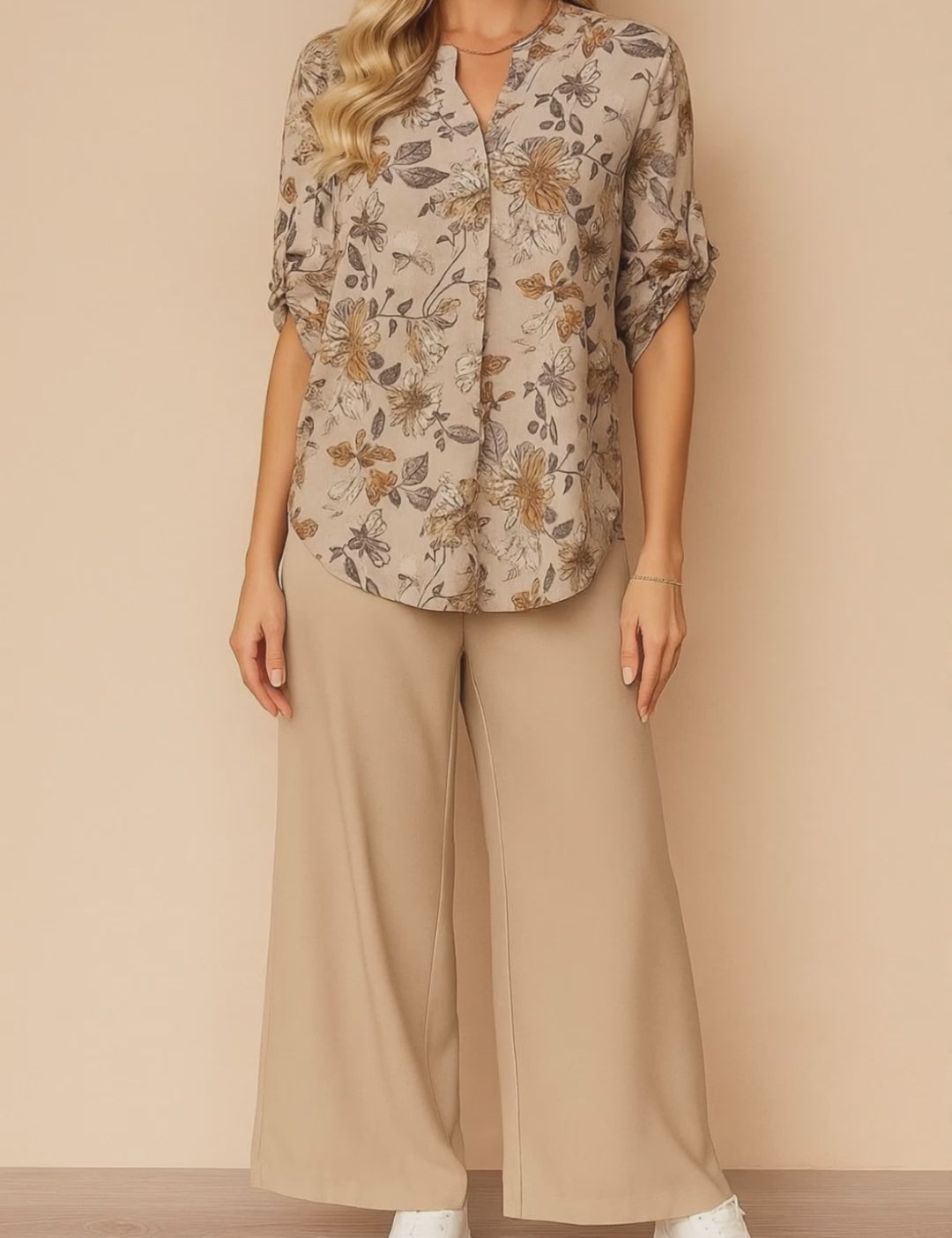 Short lookbook video of an apricot floral blouse and beige wide-leg pants two-piece set; split V-neck, roll-tab sleeves and airy, relaxed fit shown in studio lighting.