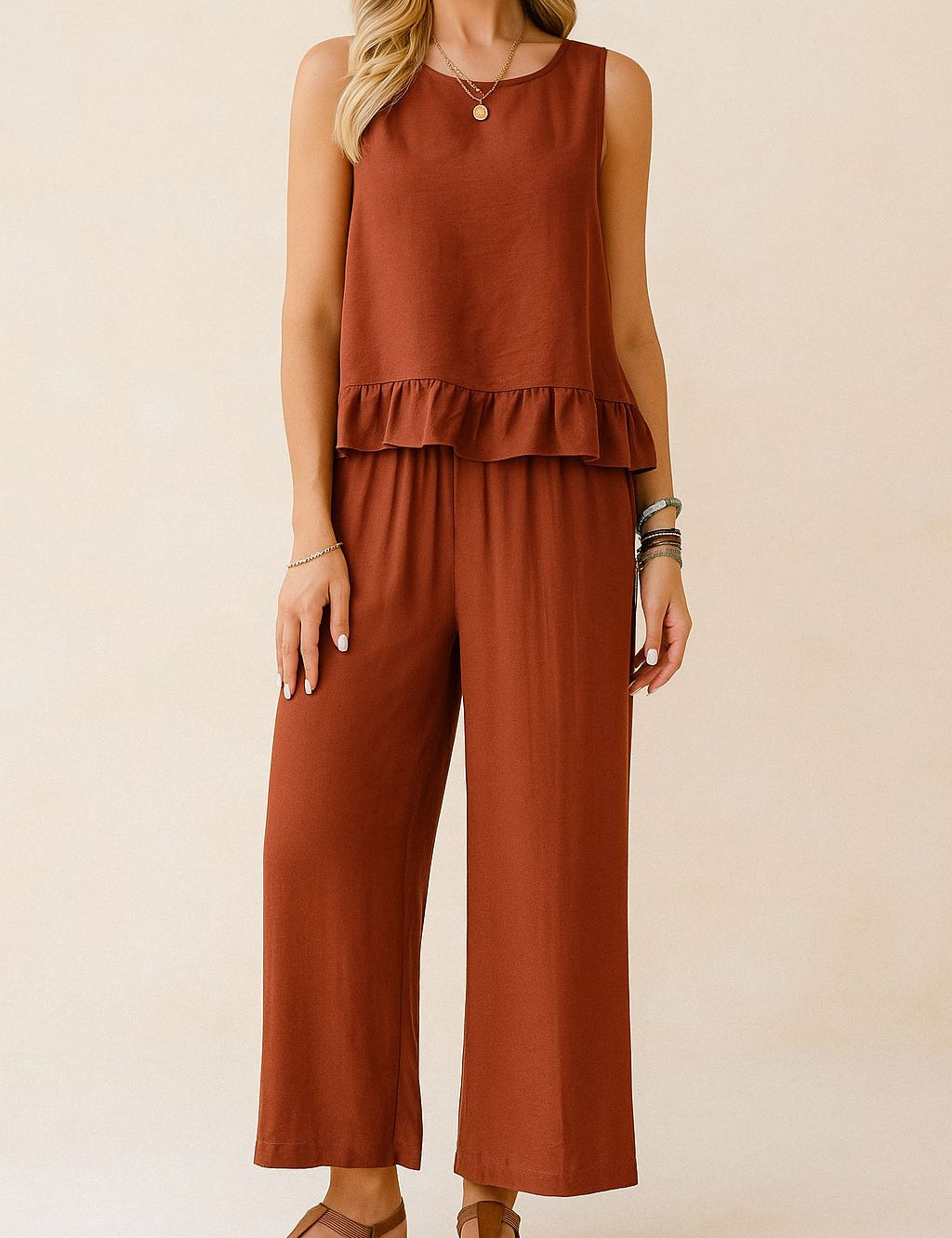 Front view of the rust two-piece set showing the sleeveless ruffle-hem top and wide-leg pants with an elastic waist; above-ankle length