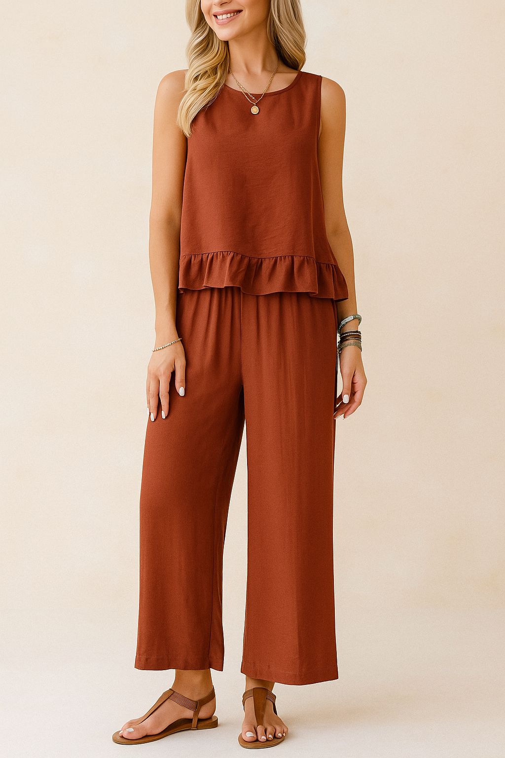 Front view of the rust two-piece set showing the sleeveless ruffle-hem top and wide-leg pants with an elastic waist; above-ankle length