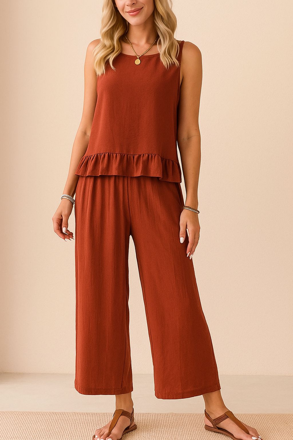 Centered front view of the rust sleeveless ruffle-hem top and matching wide-leg pants set with a relaxed drape.